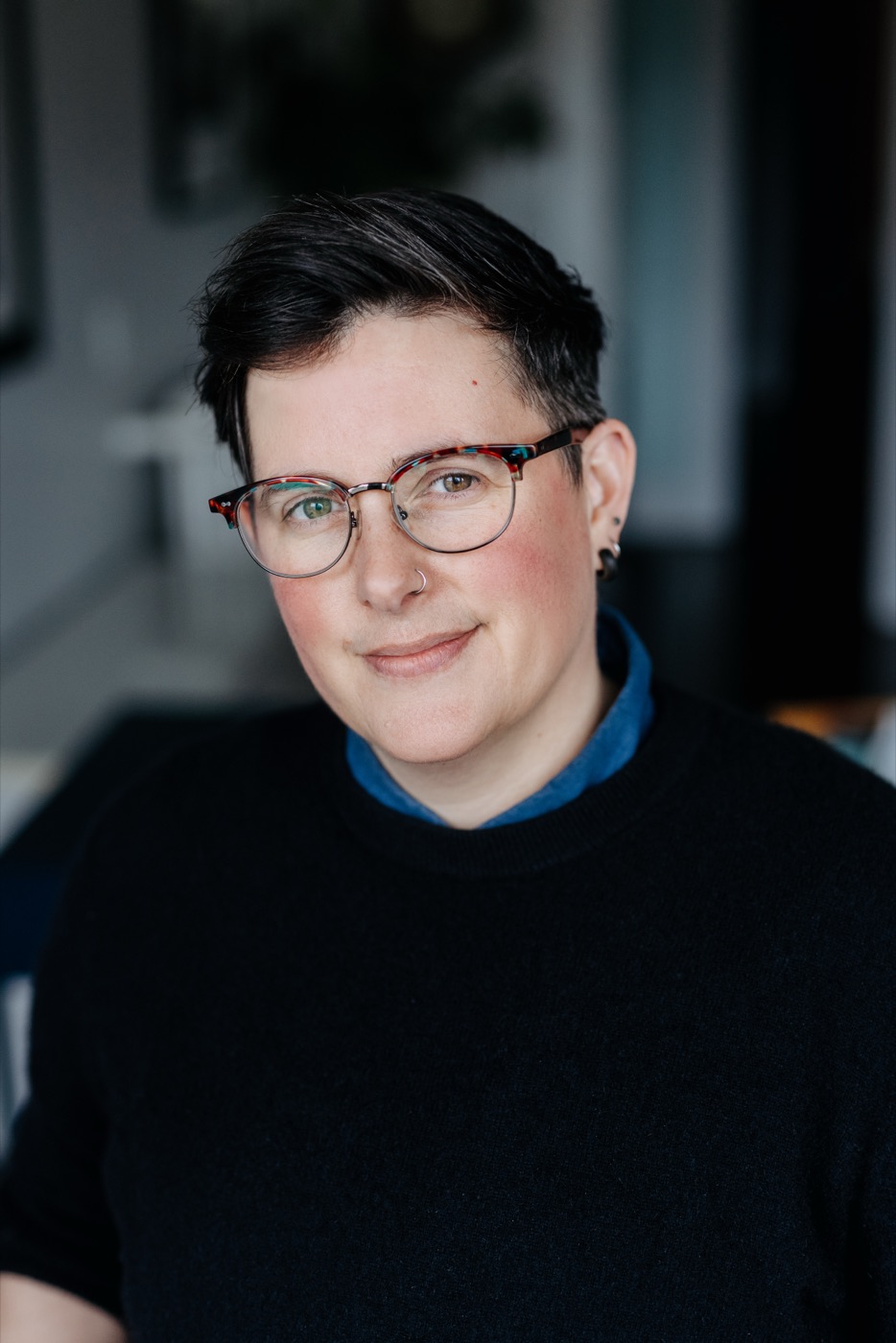 Morgan Brooks smiling at the camera, wearing glasses and a black sweater